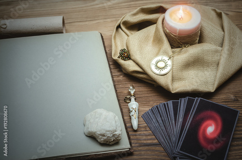 Tarot cards deck and open book of magic with copy space on fortune teller desk table bakground. Future reading concept.