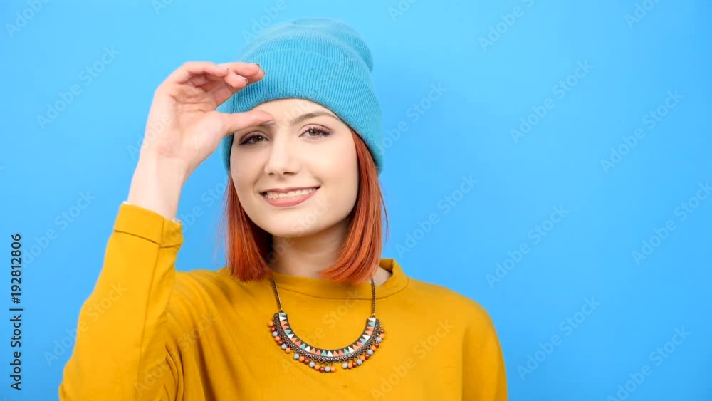 Slow motion of young cool hipster girl wearing a blue hat and playing with it on blue background Slow motion of young cool hipster girl wearing a blue hat and playing with it on blue background