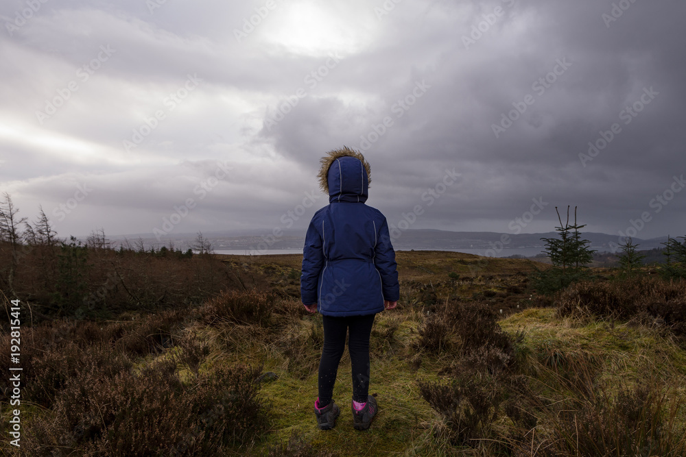 A young girl out hiking stops to take in the view 