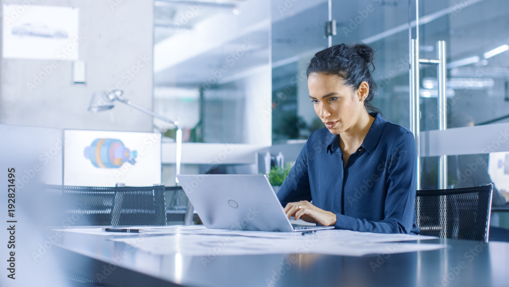 Beautiful Female Data Analyst sitting at the Table Works on a Laptop. Stylish Woman in the Modern Office Environment. Beautiful Female Data Analyst sitting at the Table Works on a Laptop. Stylish Woman in the Modern Office Environment.