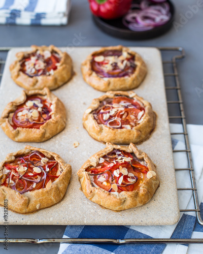 Mini pizza, vegetable galette with cream cheese, red onion, tomatoes, sweet pepper and almonds
