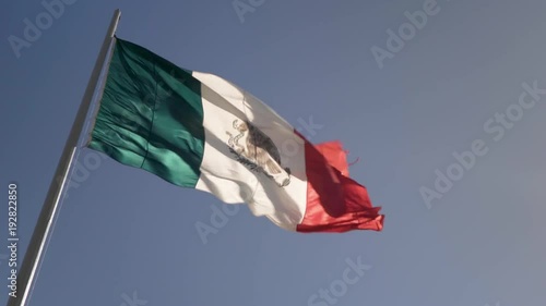 Front lit small Mexican flag waving in the wind. photo
