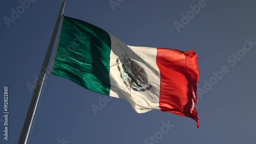 Facing right, large slow motion of back lit Mexican flag waving in the wind. photo