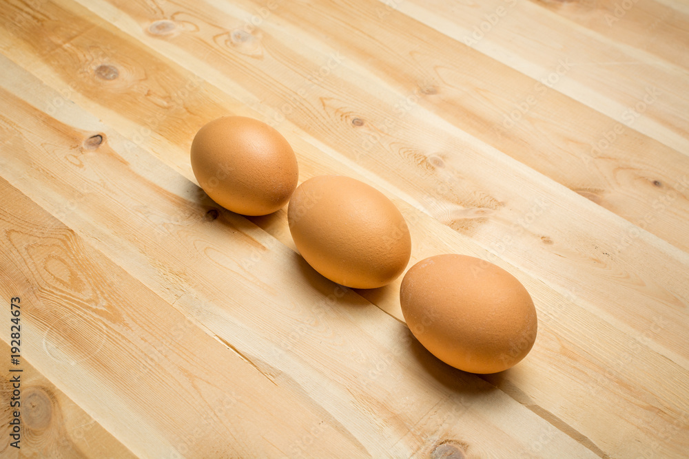 Three chicken eggs lie on a wooden board Three chicken eggs lie on a wooden board
