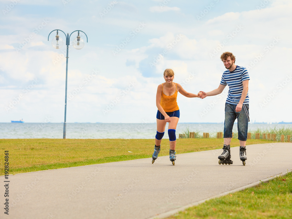 Obraz premium Young couple on roller skates riding outdoors