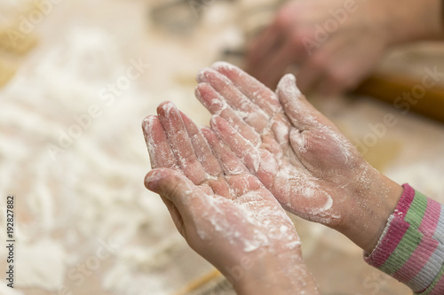Baby hands in flour. rolls out the dough.