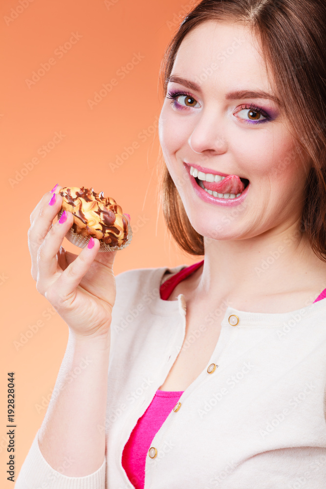 woman holds cake in hand licking lips woman holds cake in hand licking lips