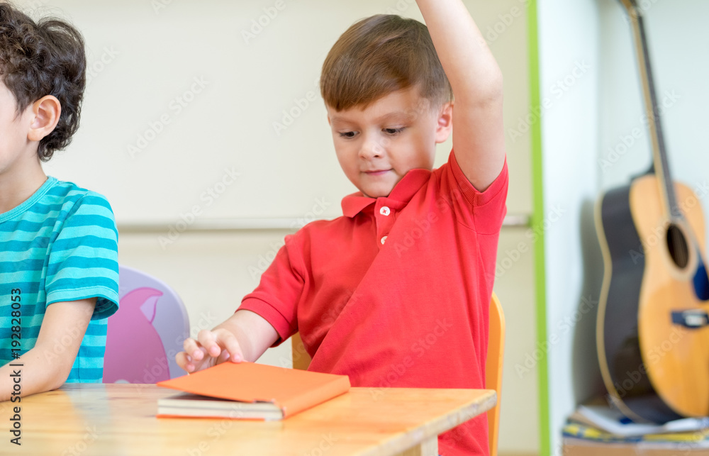Preschool kid raise arm up to answer teacher question on whiteboard in classroom,Kindergarten education concept