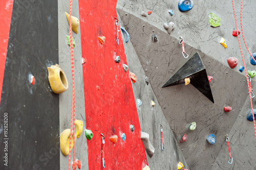 Red-gray wall of climbing wall, with ledges and ropes with carbines