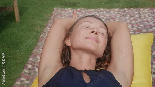 woman relaxes in a bag-chair on a clearing with green grass