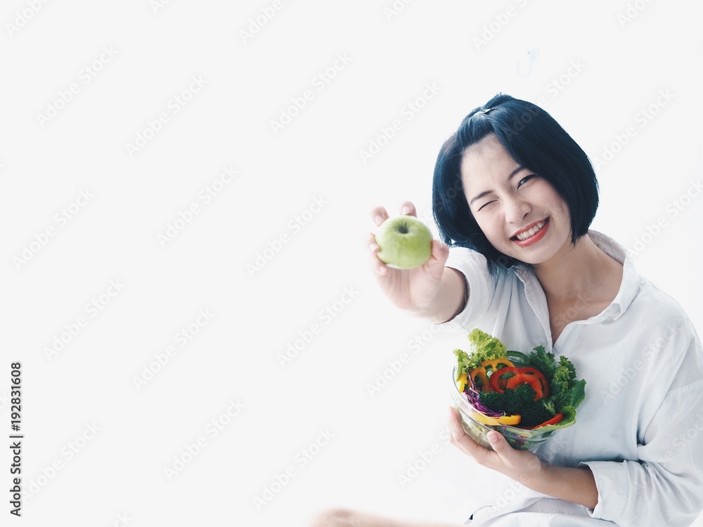 Young Asian woman holding salad bowl and fresh fruit,she's happy and joyful with this meal in the morning. Young Asian woman holding salad bowl and fresh fruit,she's happy and joyful with this meal in the morning.