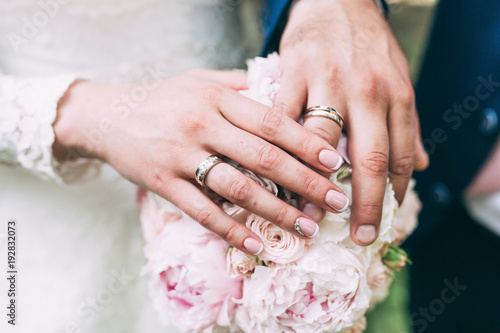 Hands of the bride and groom on a wedding bouquet