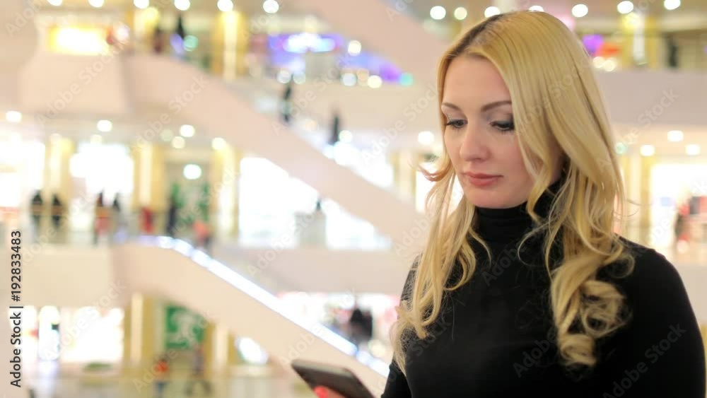 A girl in a large store talking on the phone, announces discounts for the goods A girl in a large store talking on the phone, announces discounts for the goods