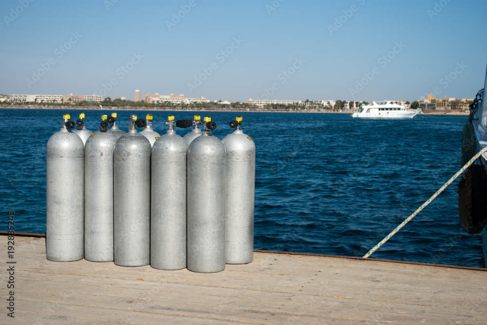 cylinders with oxygen for divers. ten cylinders on sea dock. oxygen for divers on pier. Dark blue water and steel cylinders. cylinders with oxygen for divers. ten cylinders on sea dock. oxygen for divers on pier. Dark blue water and steel cylinders.