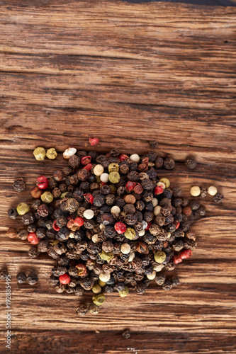 Top view on black, red and white peppercorns isolated on wooden background, shallow depth of field.