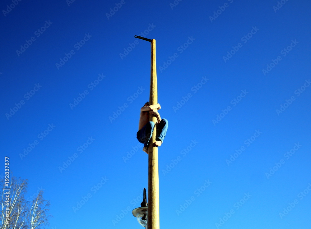 The man climbed on a wooden pole during the Maslennitsa holiday.