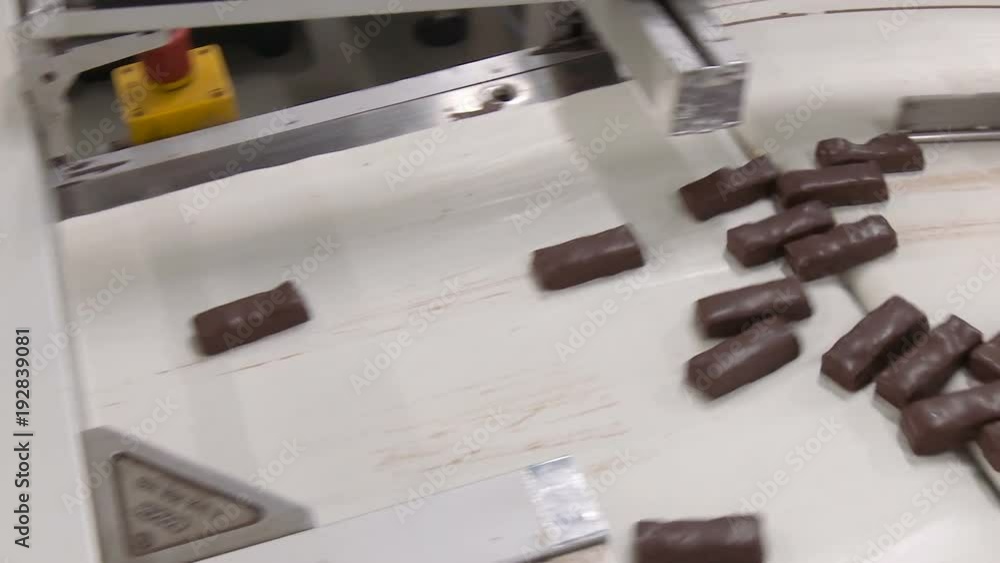 Chocolate bars move along conveyor belt at confectionery factory for