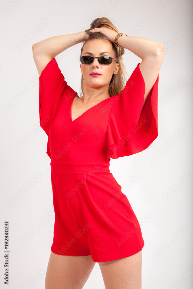 serious looking girl in red with sunglasses doing her hair serious looking girl in red with sunglasses doing her hair