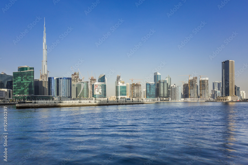 Obraz premium Panoramic view of construction at the Business Bay and downtown area of Dubai, yachts and boats sailing on Dubai creek.