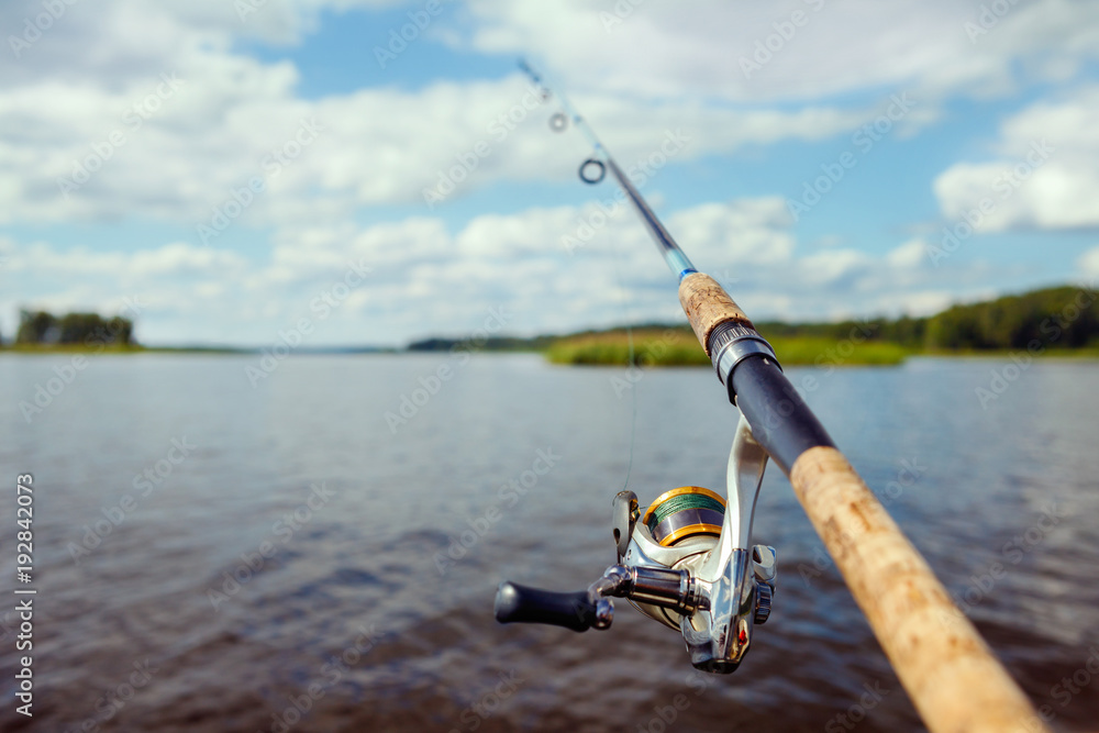 fishing rod on the background of a blurred islet of green grass. fishing rod on the background of a blurred islet of green grass.