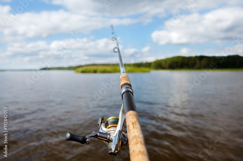 fishing rod on the background of a blurred islet of green grass.