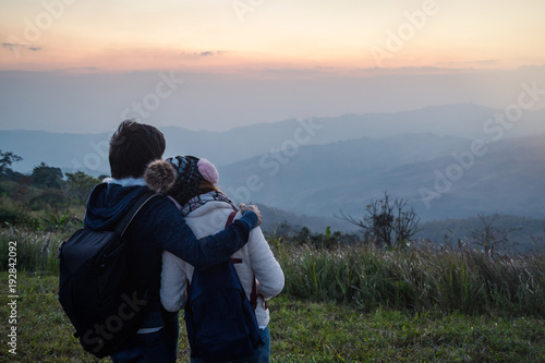 Loving couple embracing on the mountain at sunset.