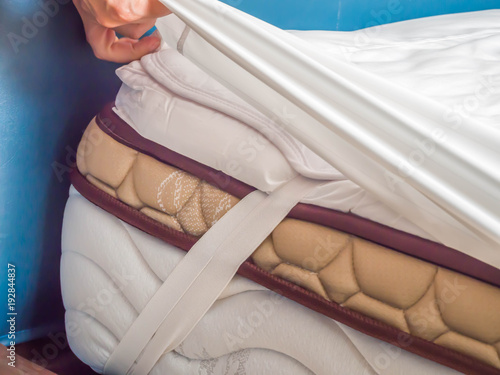Woman is putting the bedding cover or mattress pad on the bed or putting off for cleaning process.