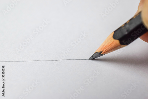 Drawing a line on white paper with a pencil