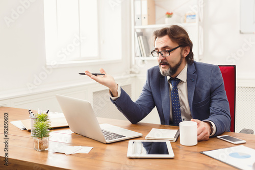 Stressed businessman with laptop in modern office