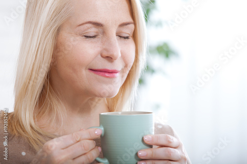 Portrait of happy blonde with mug in hands. Cup of coffee in the morning