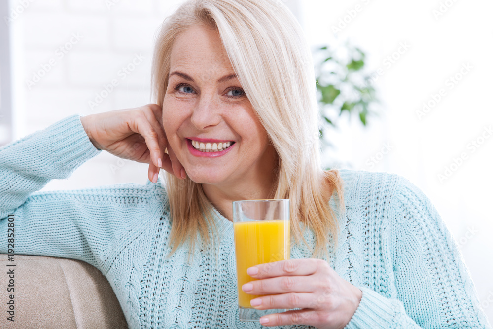Woman drinking orange juice smiling. Beautiful middle aged Caucasian model face closeup. Woman drinking orange juice smiling. Beautiful middle aged Caucasian model face closeup.