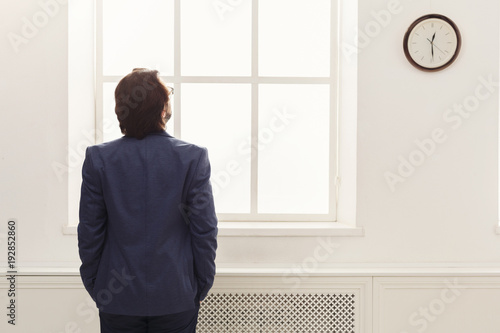 Businessman looking at clock in office. back view