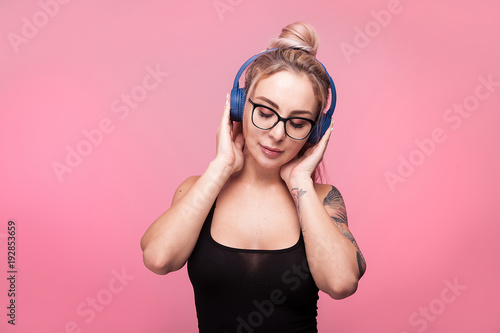 Hot woman listening to music in her head phones on pink background