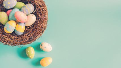 Colorful easter egg and nest on green pastel color background with space.