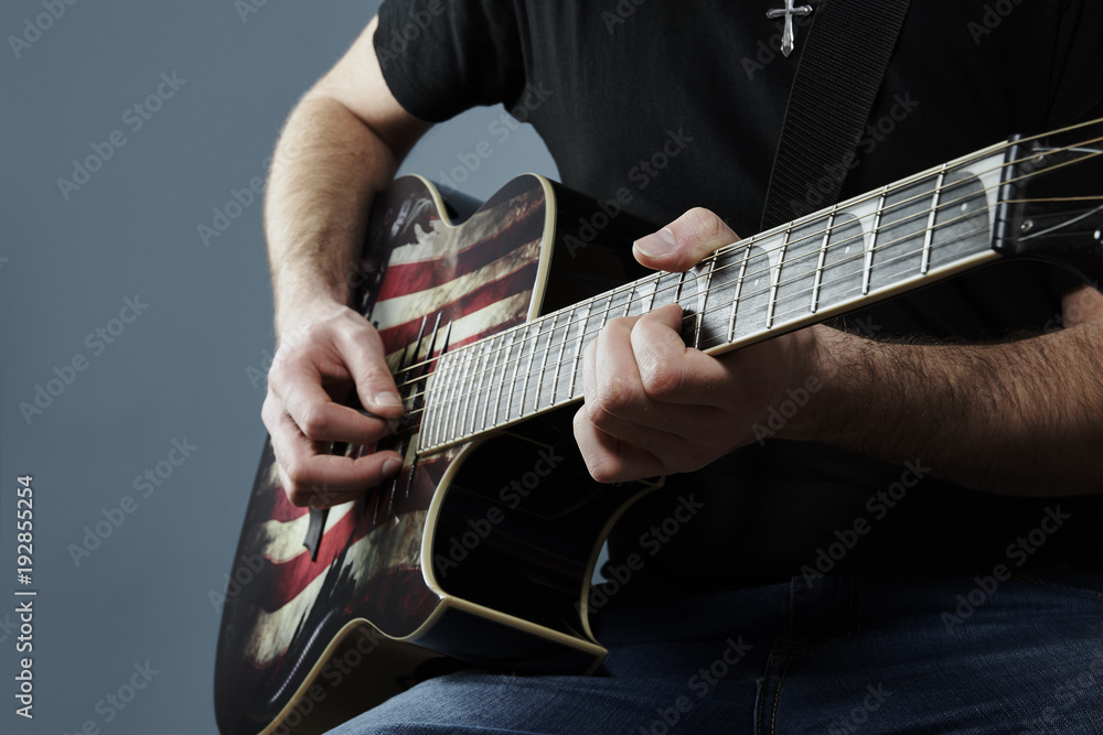 Hands of a young man playing a guitar with an American