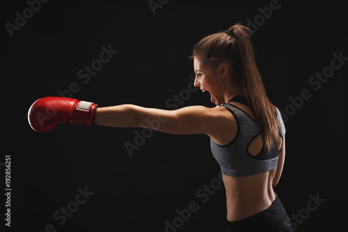 Side view of emotional young woman with boxing gloves © Prostock-studio