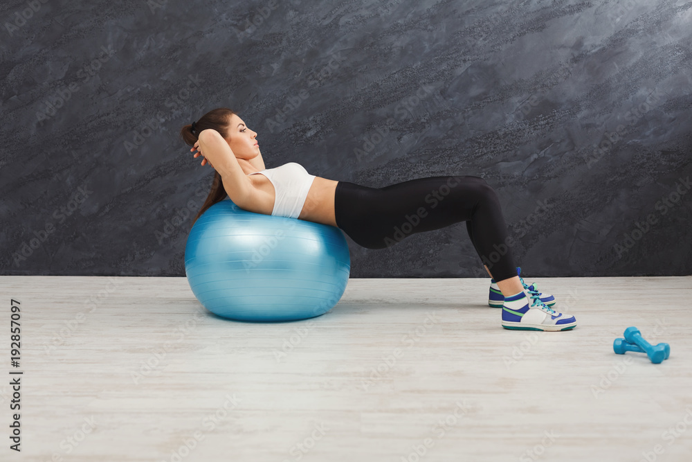 Naklejka premium Fitness woman working on her abs with fitness ball indoors