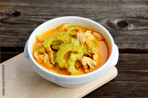 Thai Chicken Curry with Bitter Gourd in white bowl on wooden background