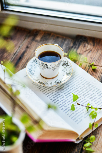 open book, coffee mug by the window, the concept of dreams and thoughtfulness
