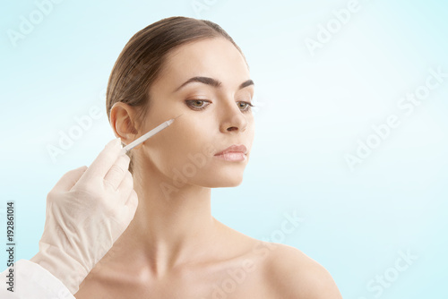 Young woman receiving cosmetic treatment with syringe injection