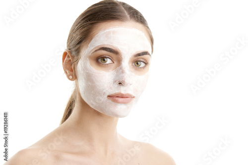 Close-up studio shot of young woman wearing a beauty face mask against at isolated white background with copy space. 