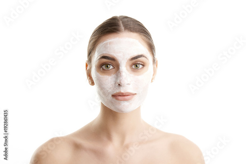 Close-up studio shot of young woman wearing a beauty face mask against at isolated white background with copy space. 