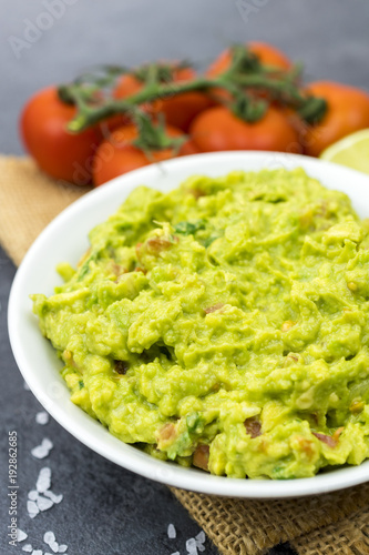 Bowl of guacamole on black wooden background.