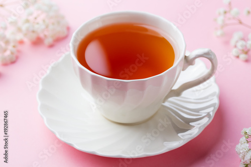 Cup of tea with fresh flowers on pink background. Copy space
