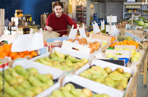 Portrait of  young customer selecting apple in grocery photo