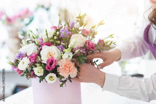 Young happy florist making fresh flowers arrangement in gift box for a holidays photo