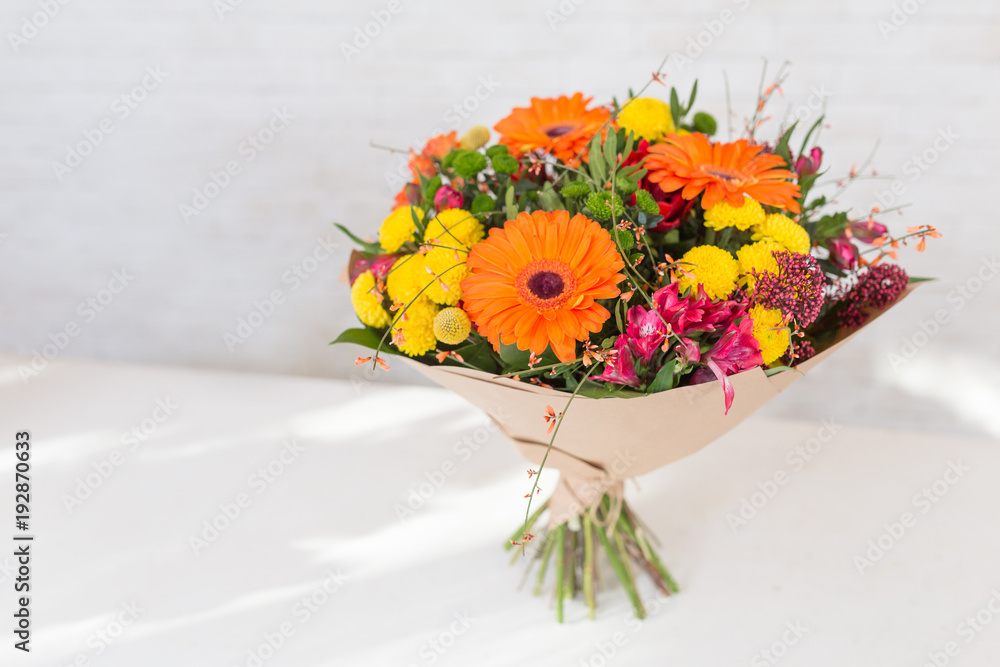 Naklejka premium Fresh and lush bouquet of colorful flowers, on white brick background with copyspace