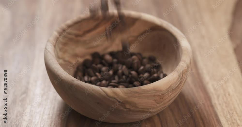 Slow motion coffee beans falling into wood bowl on table Slow motion coffee beans falling into wood bowl on table