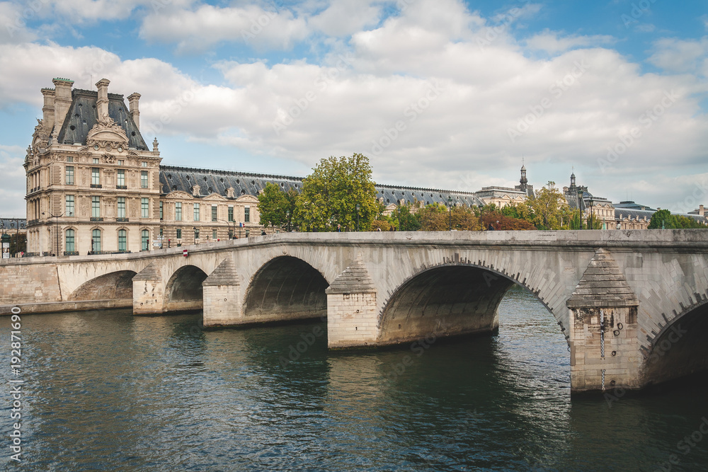 View on museum of Louvre and bridge over river Seine on bright summer day in Paris, France