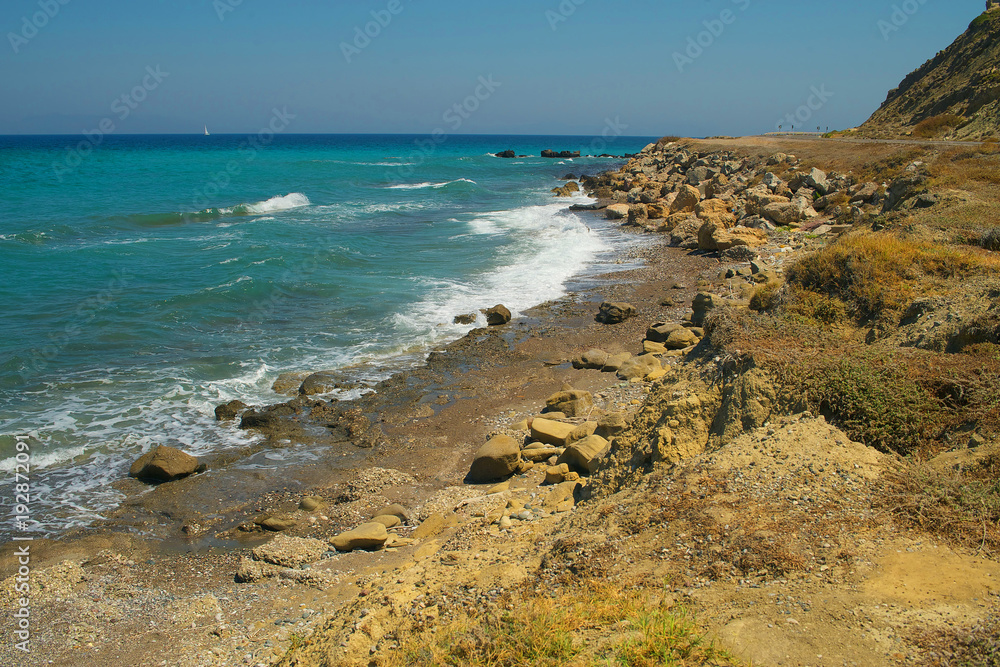 Rocky seaside with bright sea and yacht on background